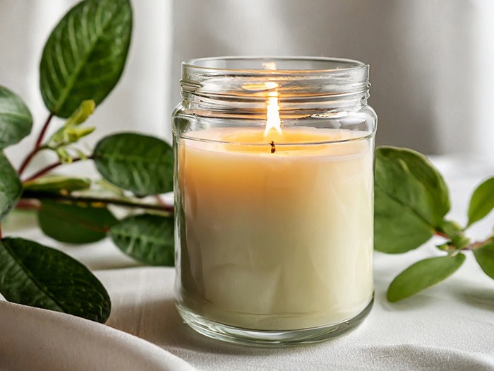 A glowing candle in a glass jar.